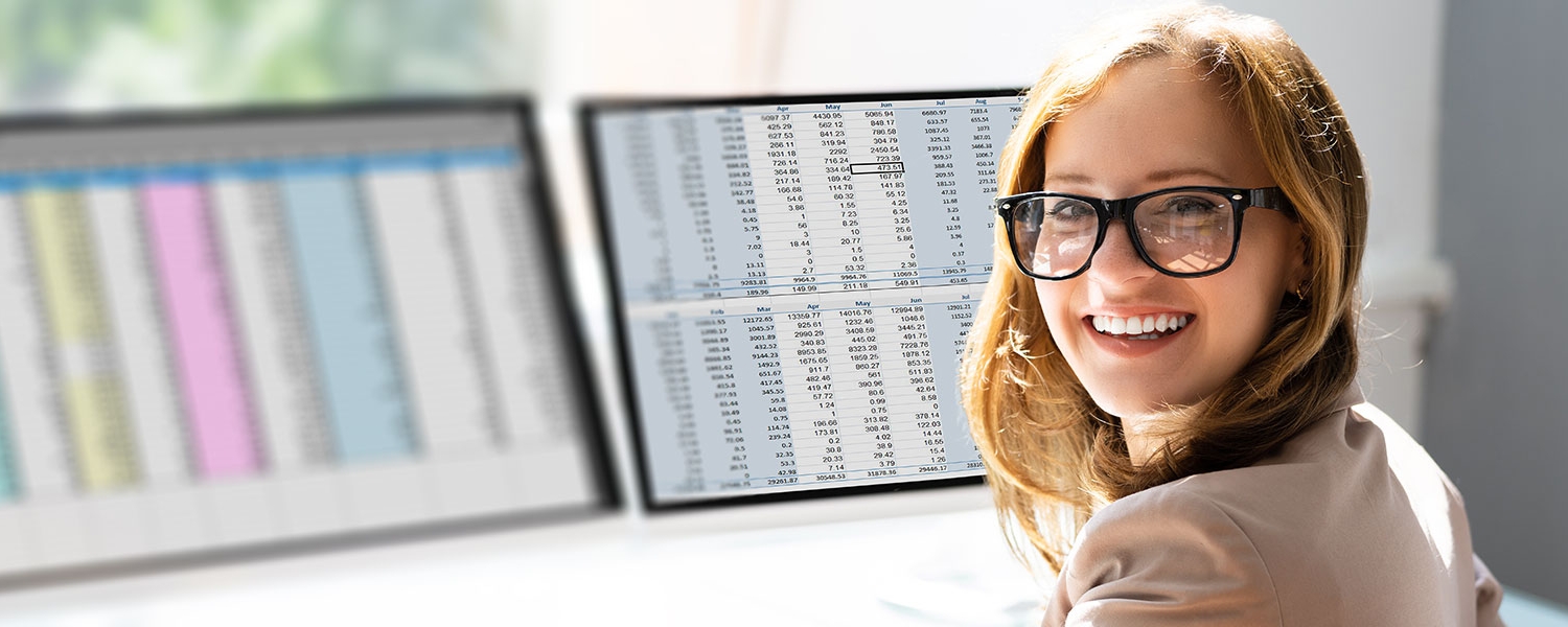 Healthcare medical scribe working on spreadsheet at desk turning facing camera
