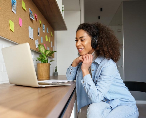 Smiling young african american woman wearing headphones on laptop