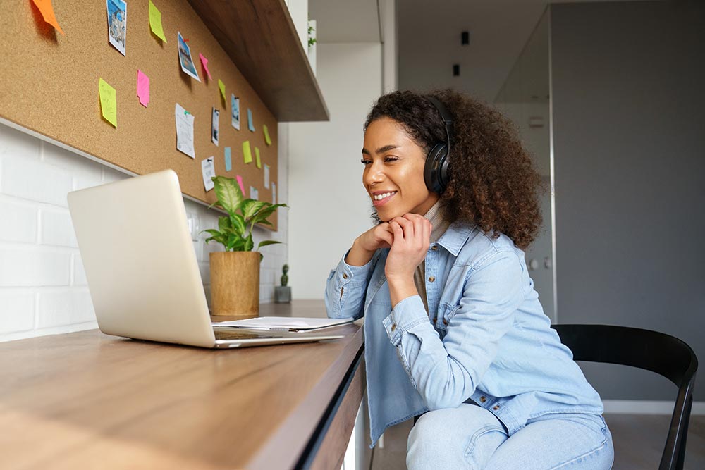 Smiling young african american woman wearing headphones on laptop